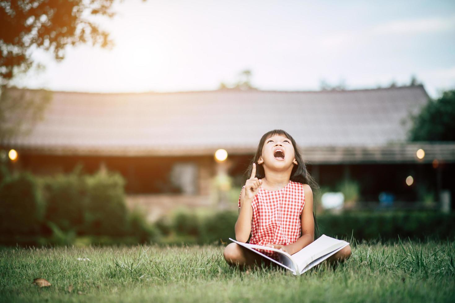 menina lendo um livro no jardim de sua casa lá fora foto