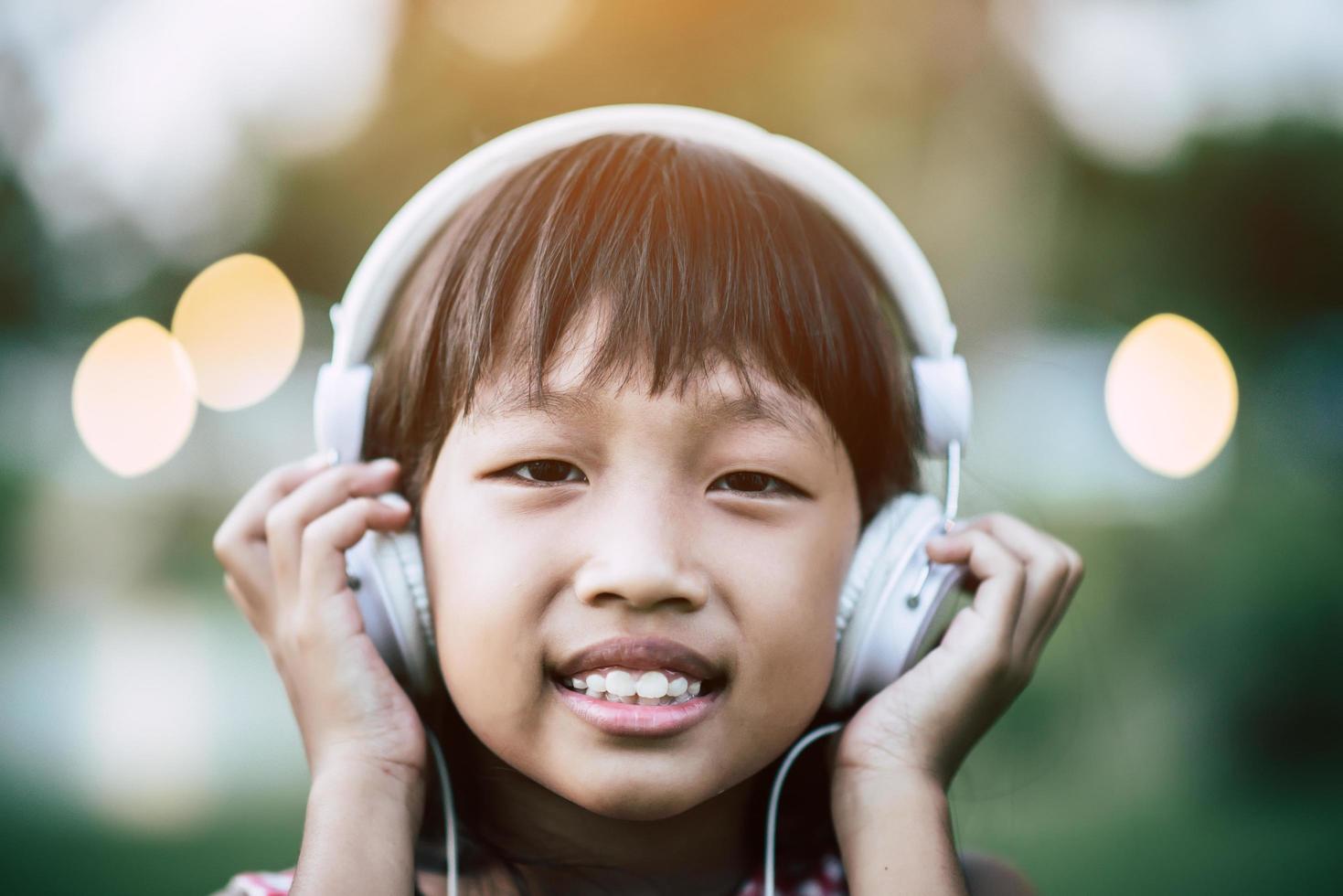 menina ouvindo música no parque com fones de ouvido foto