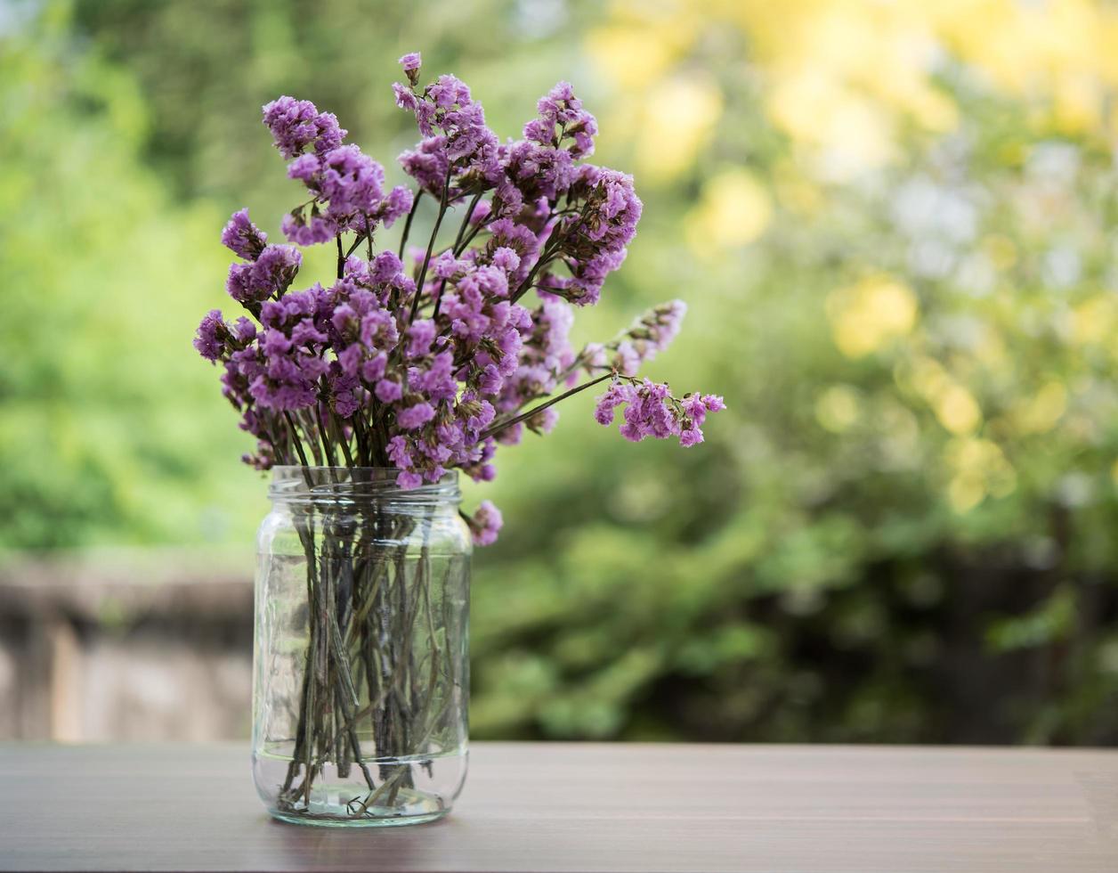 lindas flores em um vaso de vidro na mesa de madeira foto