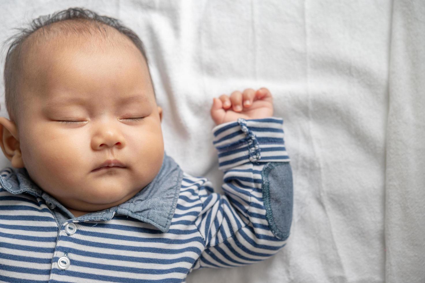 um menino com uma camisa listrada dormindo na cama foto