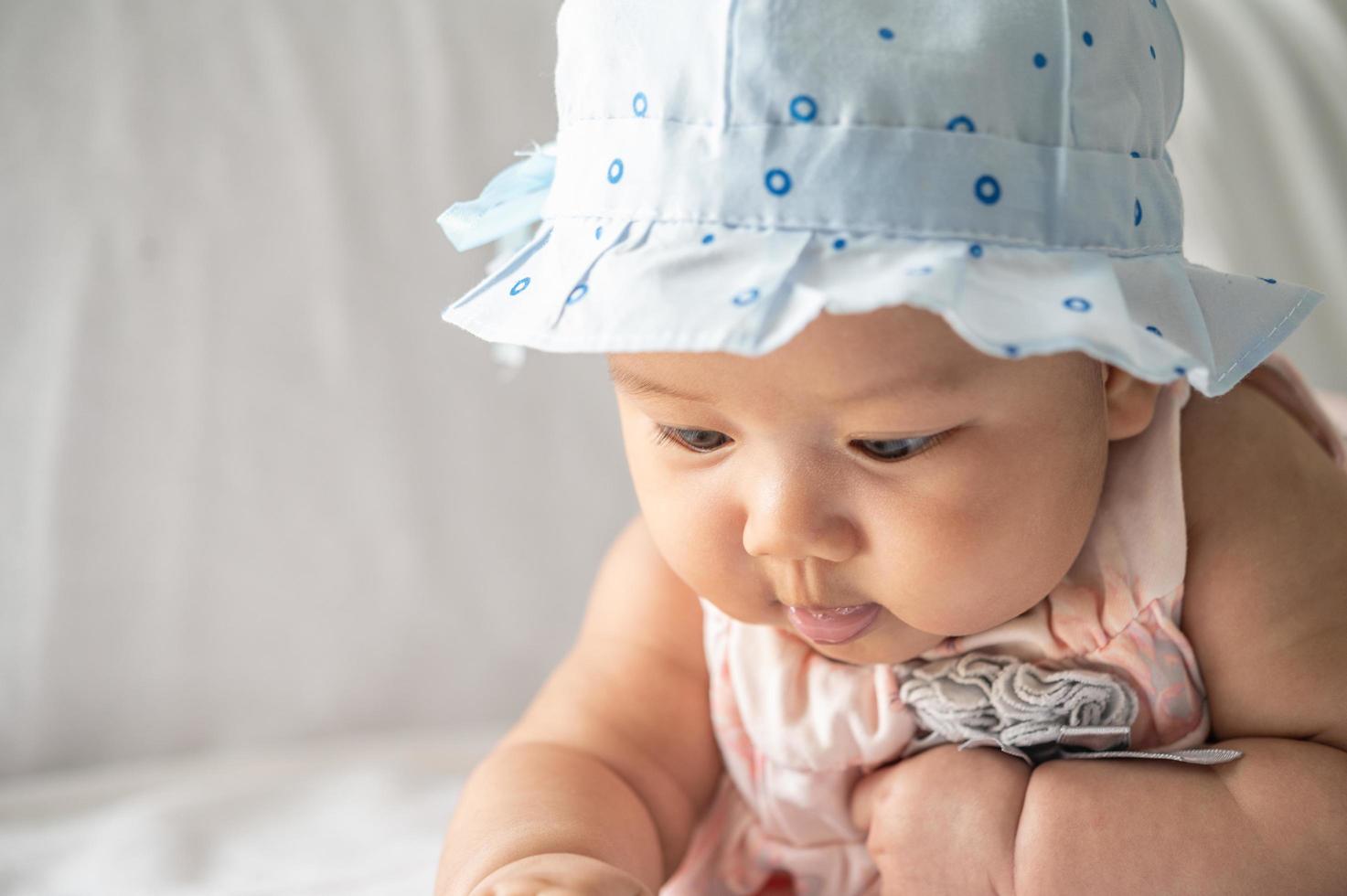 o bebê está deitado com a cabeça erguida na cama foto