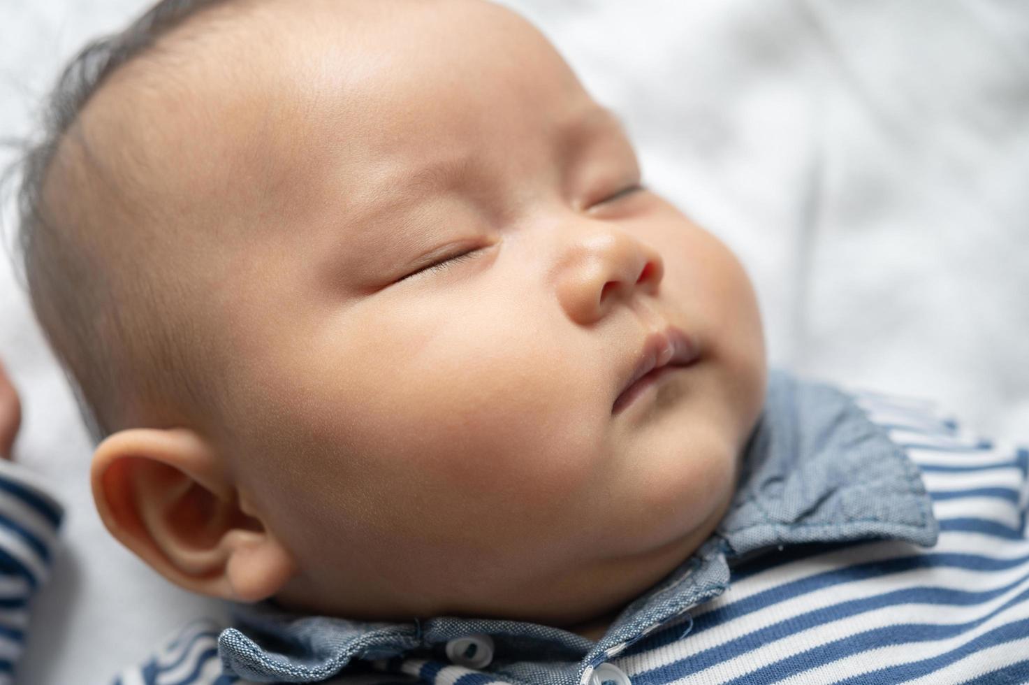 um menino com uma camisa listrada dormindo na cama foto