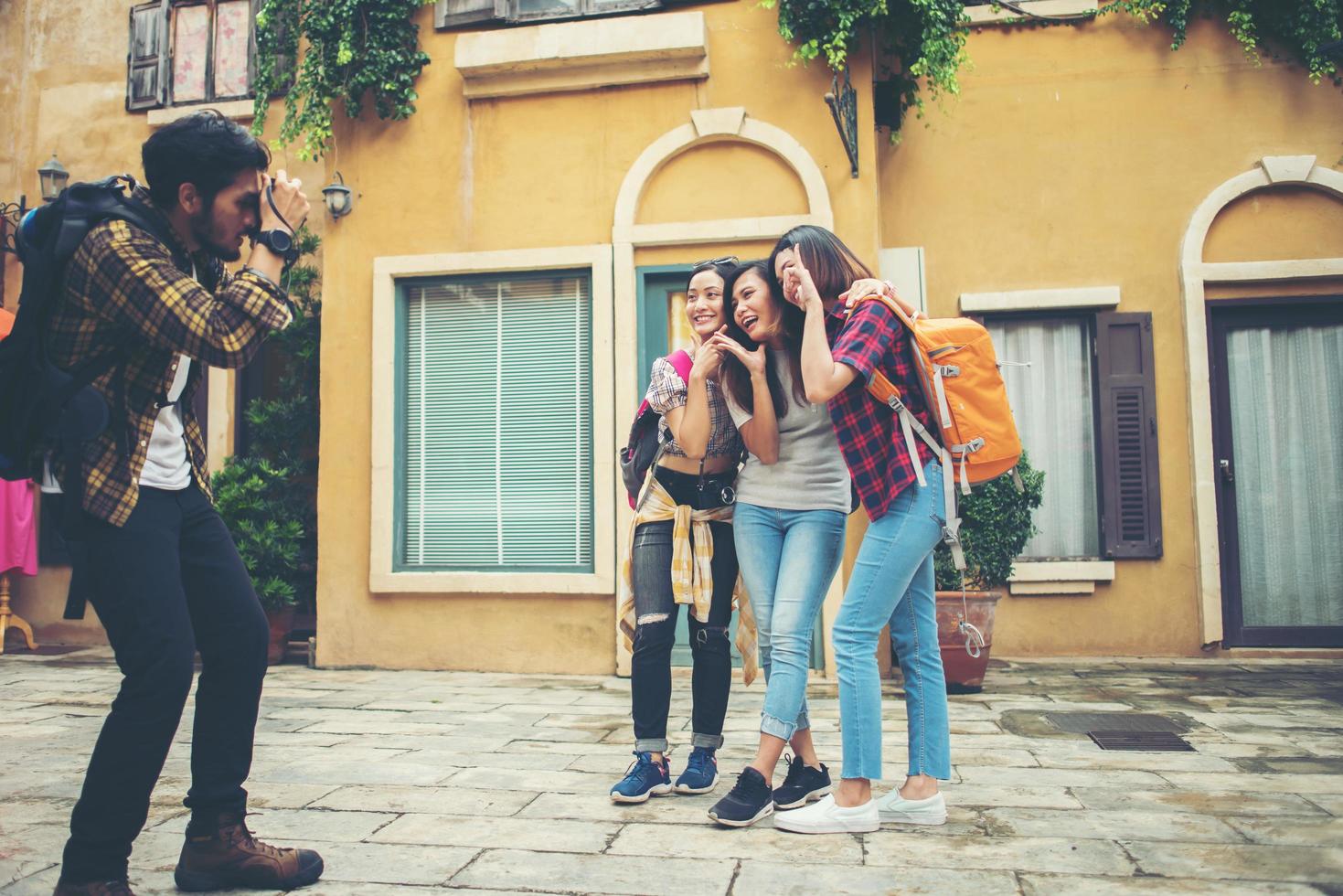 jovem tirando fotos de seus amigos enquanto viajava juntos em uma área urbana