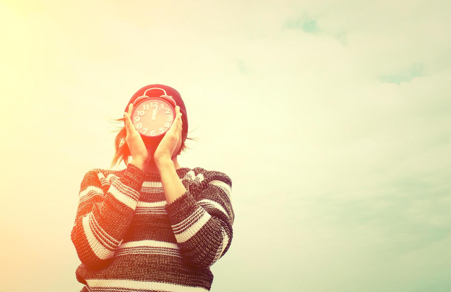 jovem segurando um despertador vermelho, conceito de tempo foto