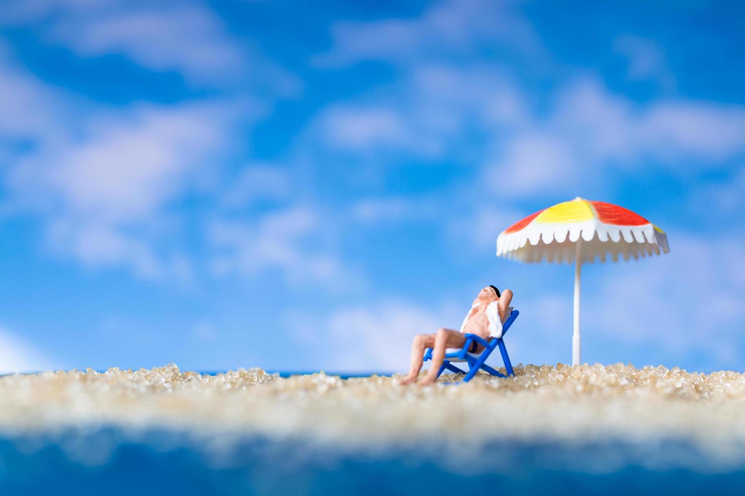 homem sentado na praia com um guarda-chuva foto