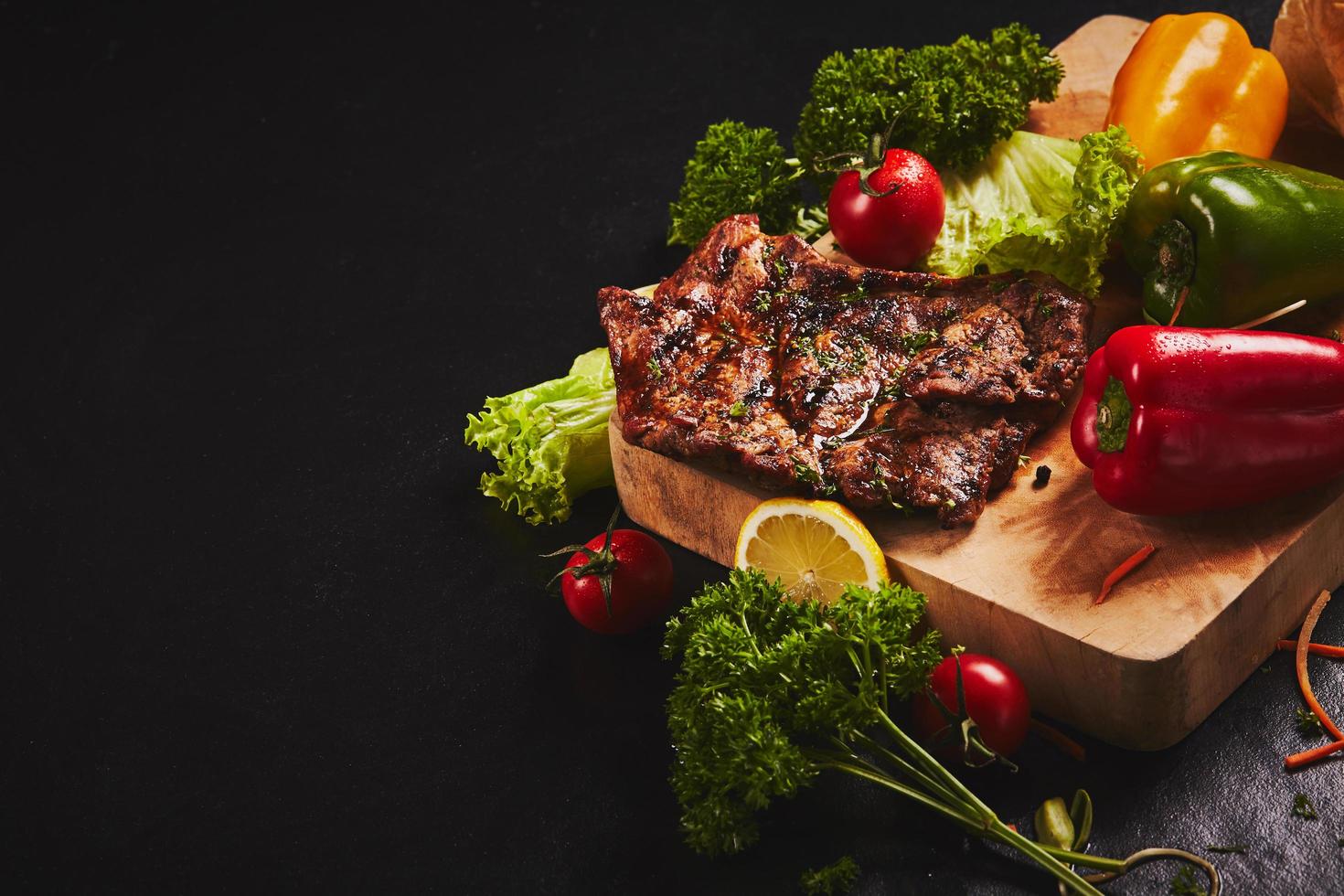 bife e legumes em fundo escuro foto