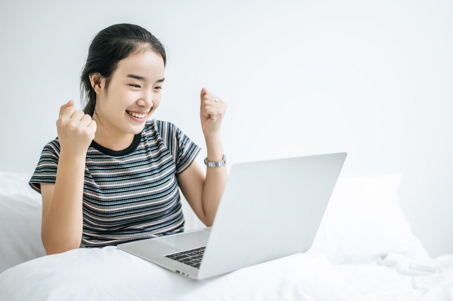 uma jovem brincando em seu laptop na cama foto