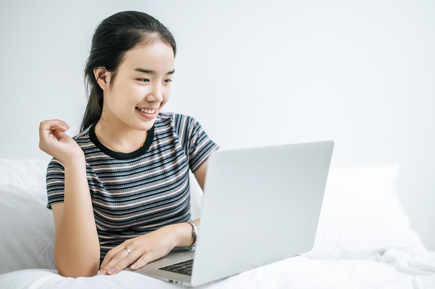 uma jovem brincando em seu laptop na cama foto