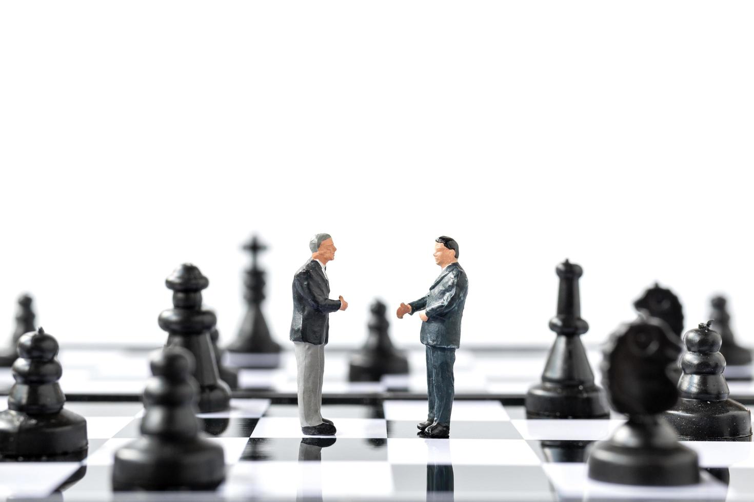 estatuetas em miniatura de empresários em pé no tabuleiro de xadrez foto