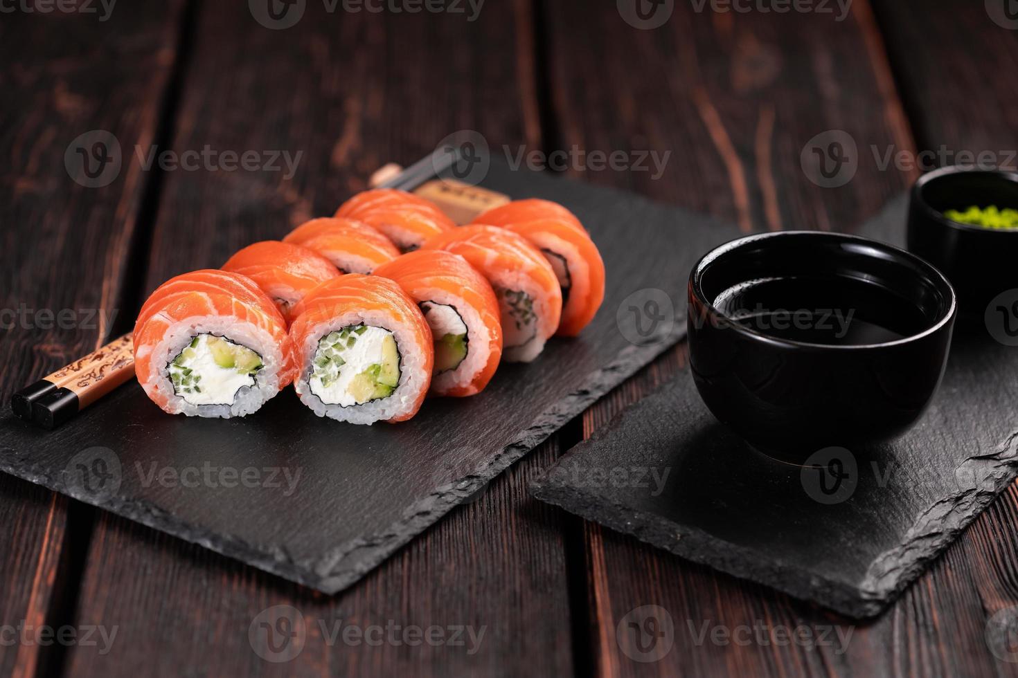 sushi roll philadelphia com salmão e pepino com abacate e cream cheese em fundo preto. cardápio de sushi. conceito de comida japonesa foto