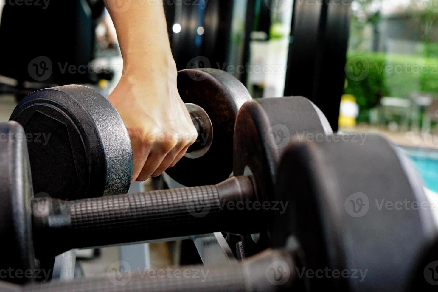 feche a mão segurando o haltere em fitness. conceito de exercício e cuidados de saúde. foto