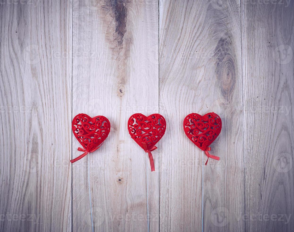 três corações vermelhos esculpidos em uma vara foto