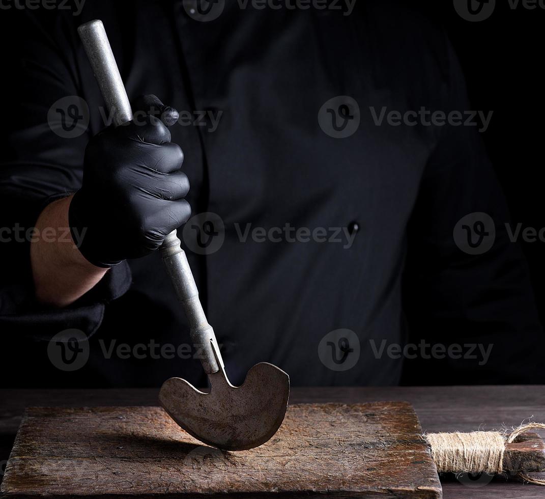 chef em roupas pretas tem na mão uma faca velha de metal foto