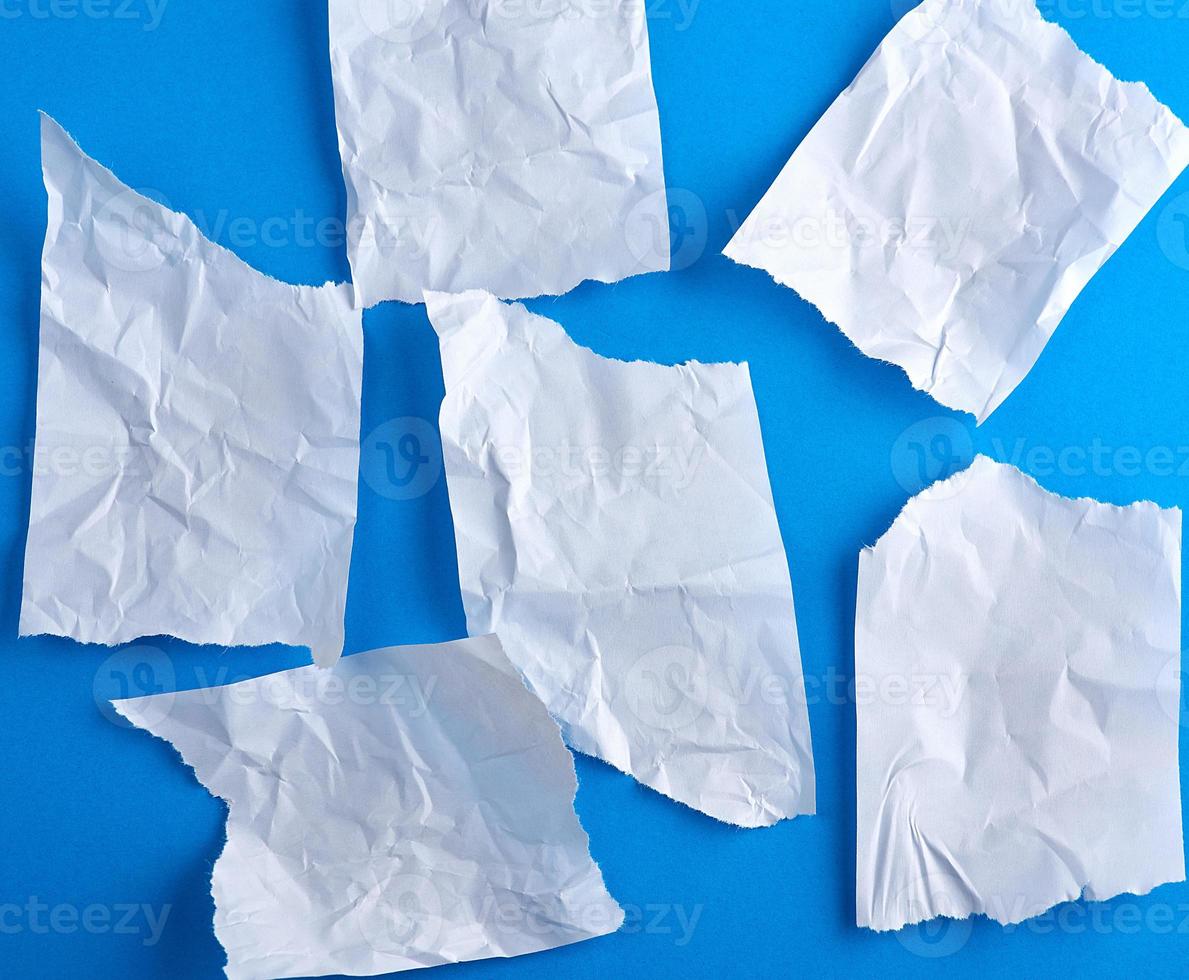 pedaços rasgados vazios amassados de papel branco sobre um fundo azul foto