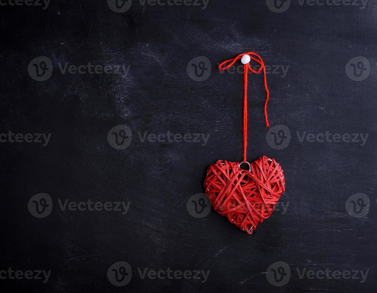 pequeno coração vermelho de vime paira sobre uma corda foto