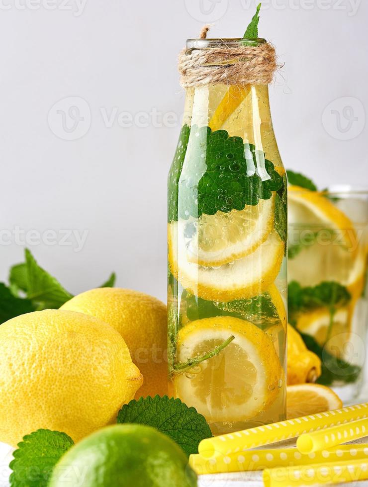 bebida refrescante de verão limonada com limões, folhas de hortelã, limão em uma garrafa de vidro foto