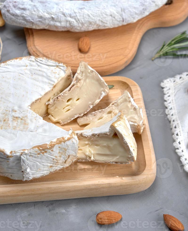 queijo brie redondo em uma tábua de madeira foto