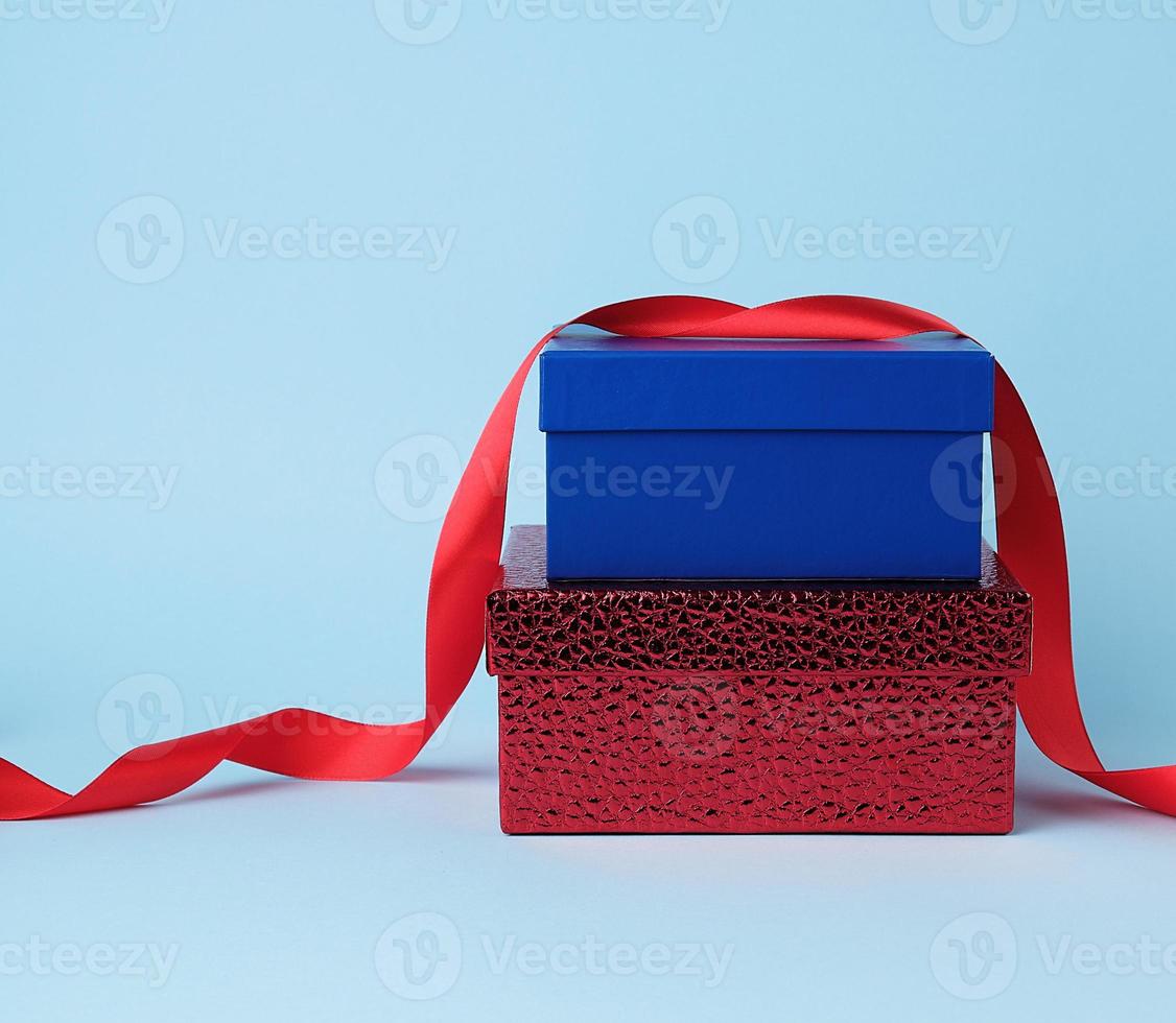 caixas de papelão quadradas azuis e vermelhas para presente e fita vermelha de seda torcida foto