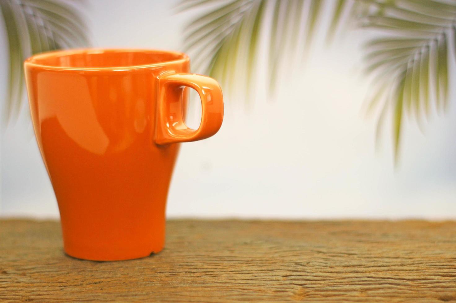 xícara de café laranja em madeira foto