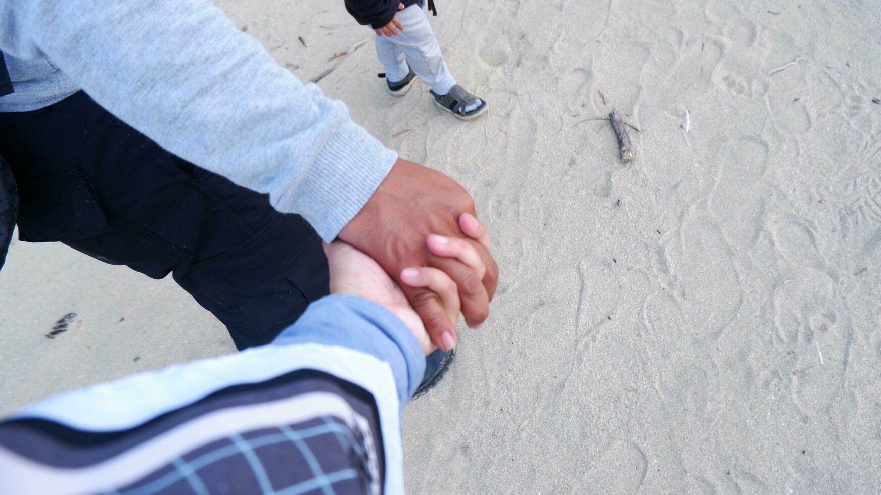 um casal andando de mãos dadas na praia com um fundo de areia da praia foto