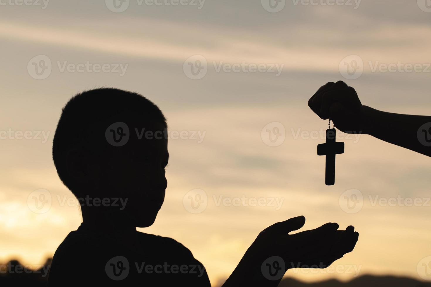 silhueta de um homem rezando com uma cruz na mão ao nascer do sol, conceito de religião. foto