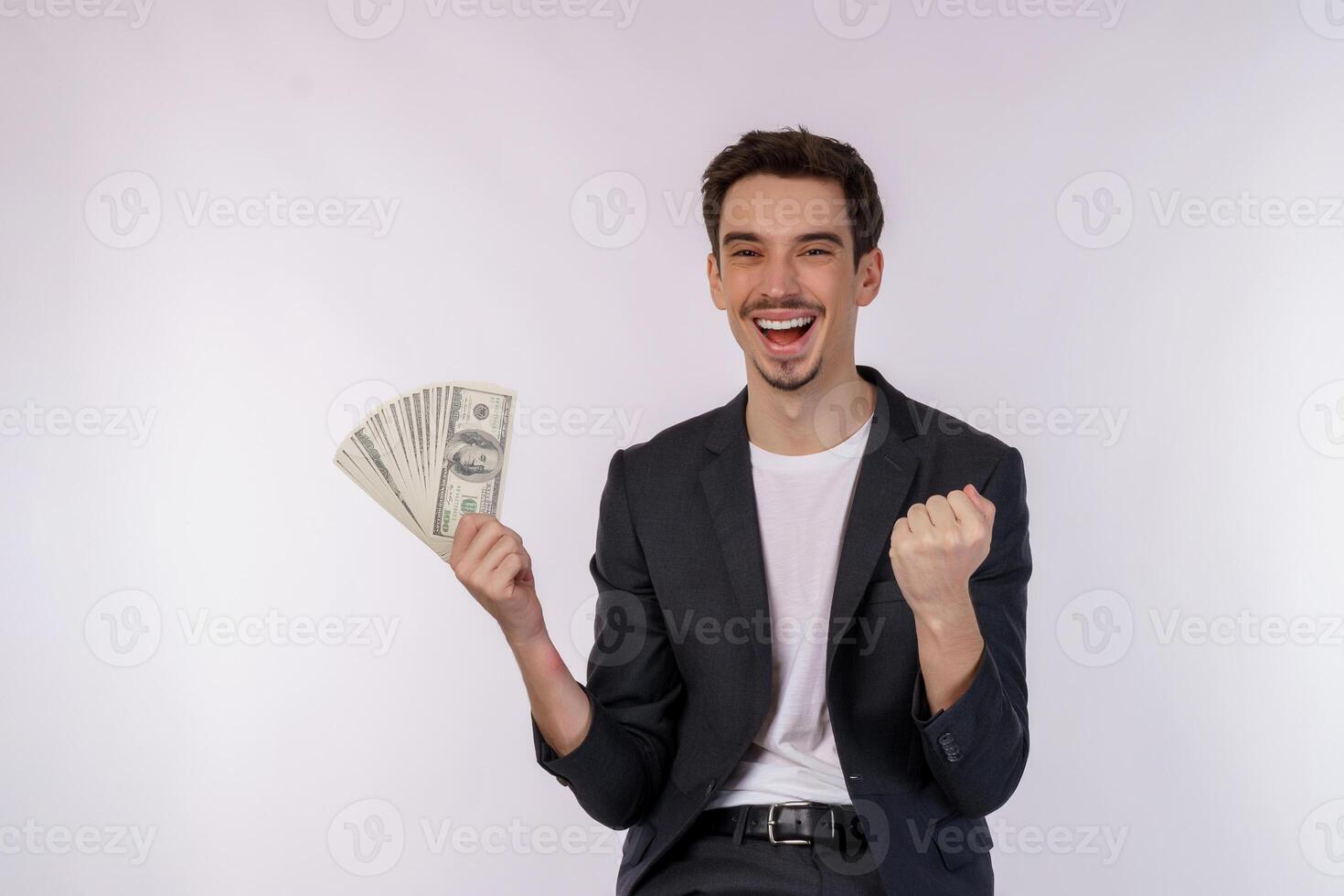 retrato de um homem alegre segurando notas de dólar e fazendo gesto de vencedor cerrando o punho sobre fundo branco foto