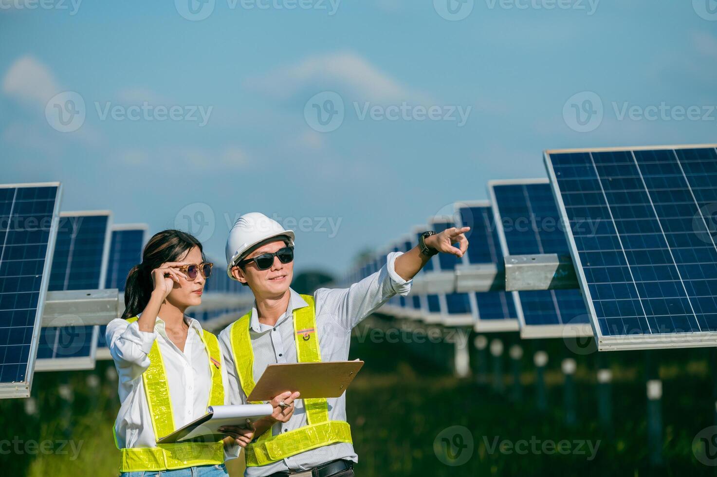 jovem inspetor asiático engenheiro homem e mulher caminhando verificando a operação na fazenda solar foto