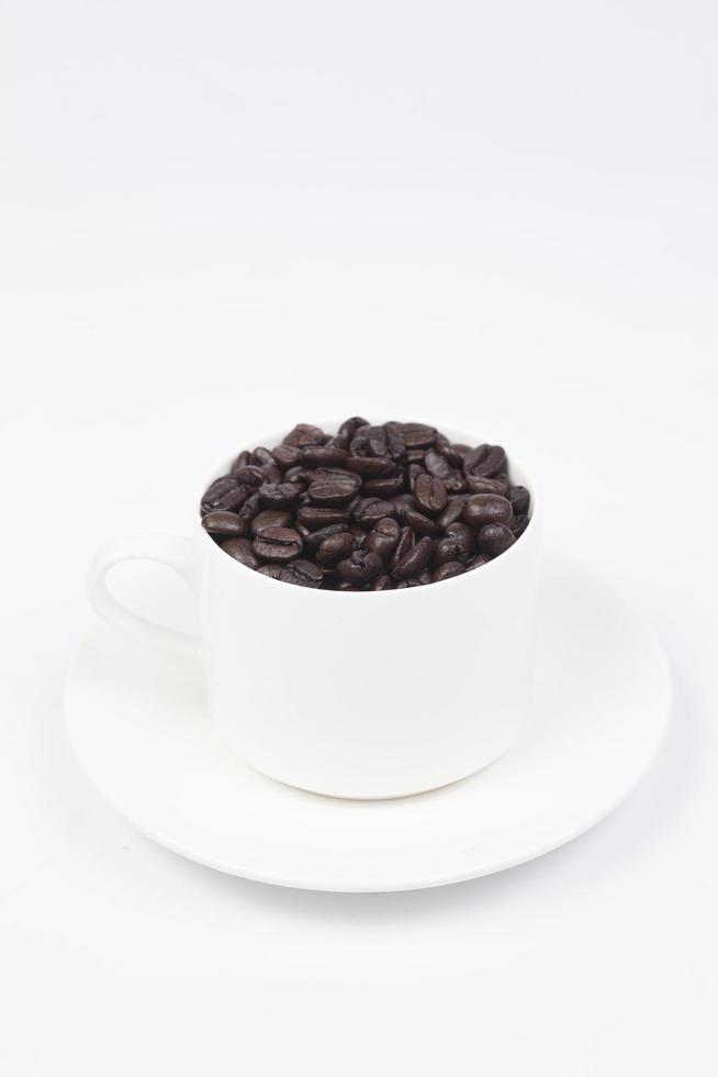 xícara com grãos de café no fundo branco foto