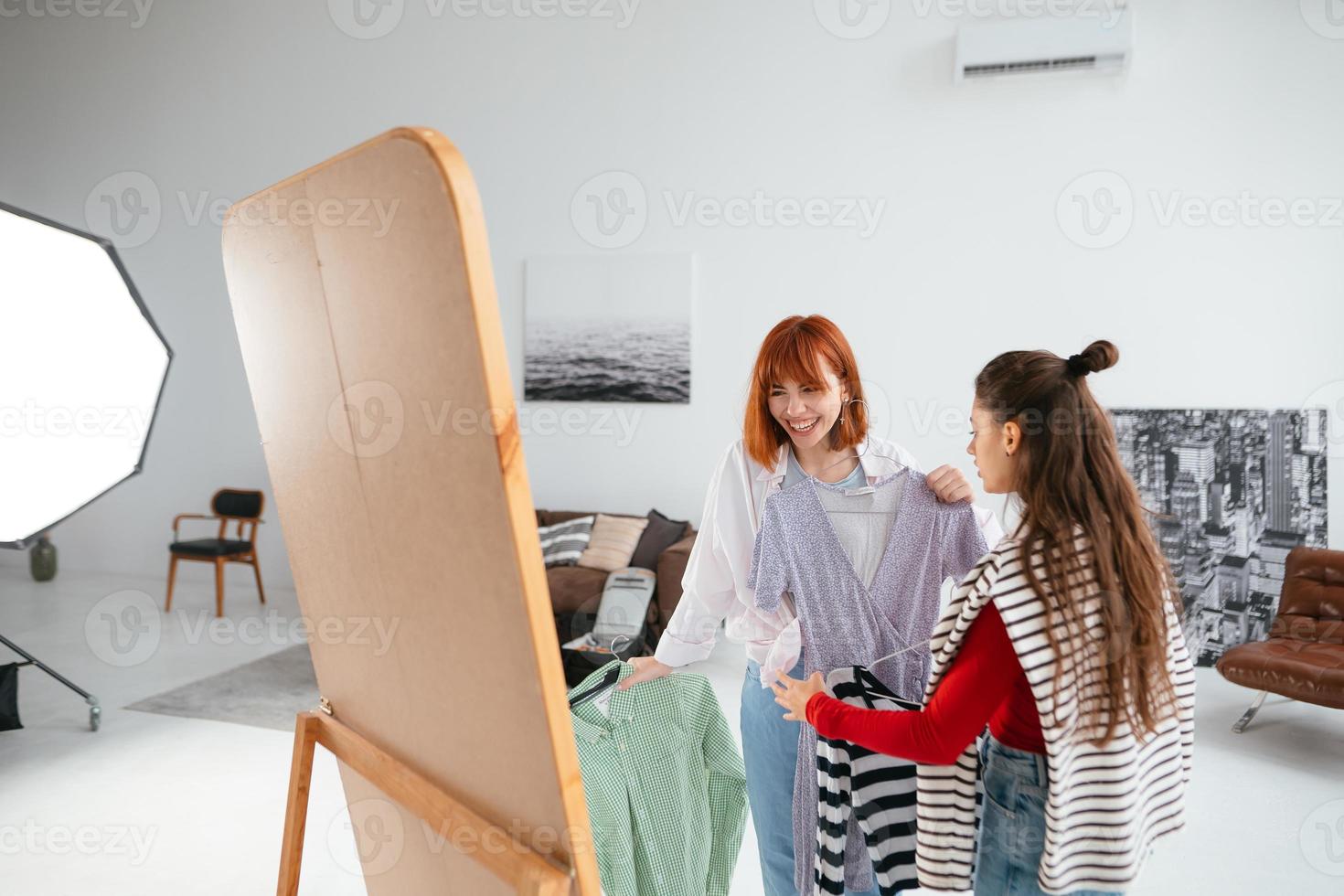 mulher jovem e bonita feliz escolhendo roupas com a namorada. foto