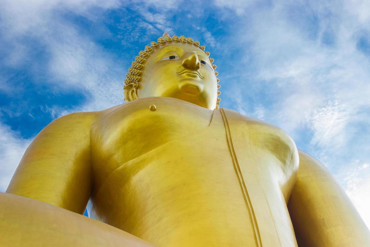 estátua de Buda dourado com céu azul nublado foto