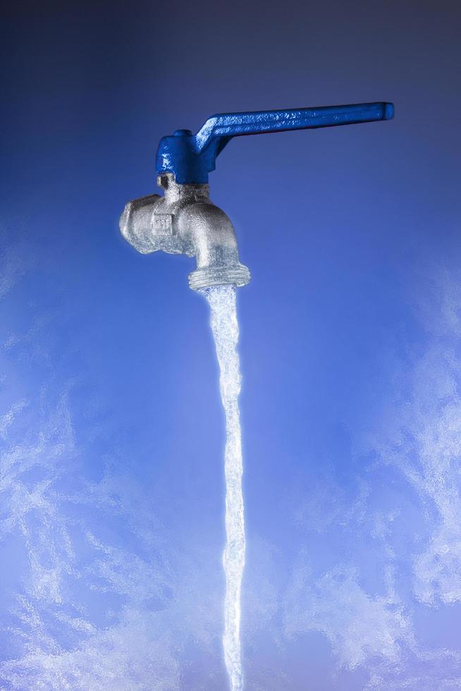 água fluindo da torneira com alavanca azul sobre fundo azul foto