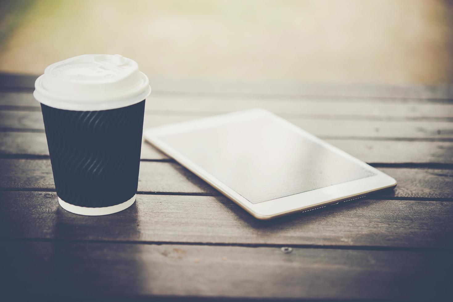 tablet digital na mesa de madeira com uma xícara de café foto