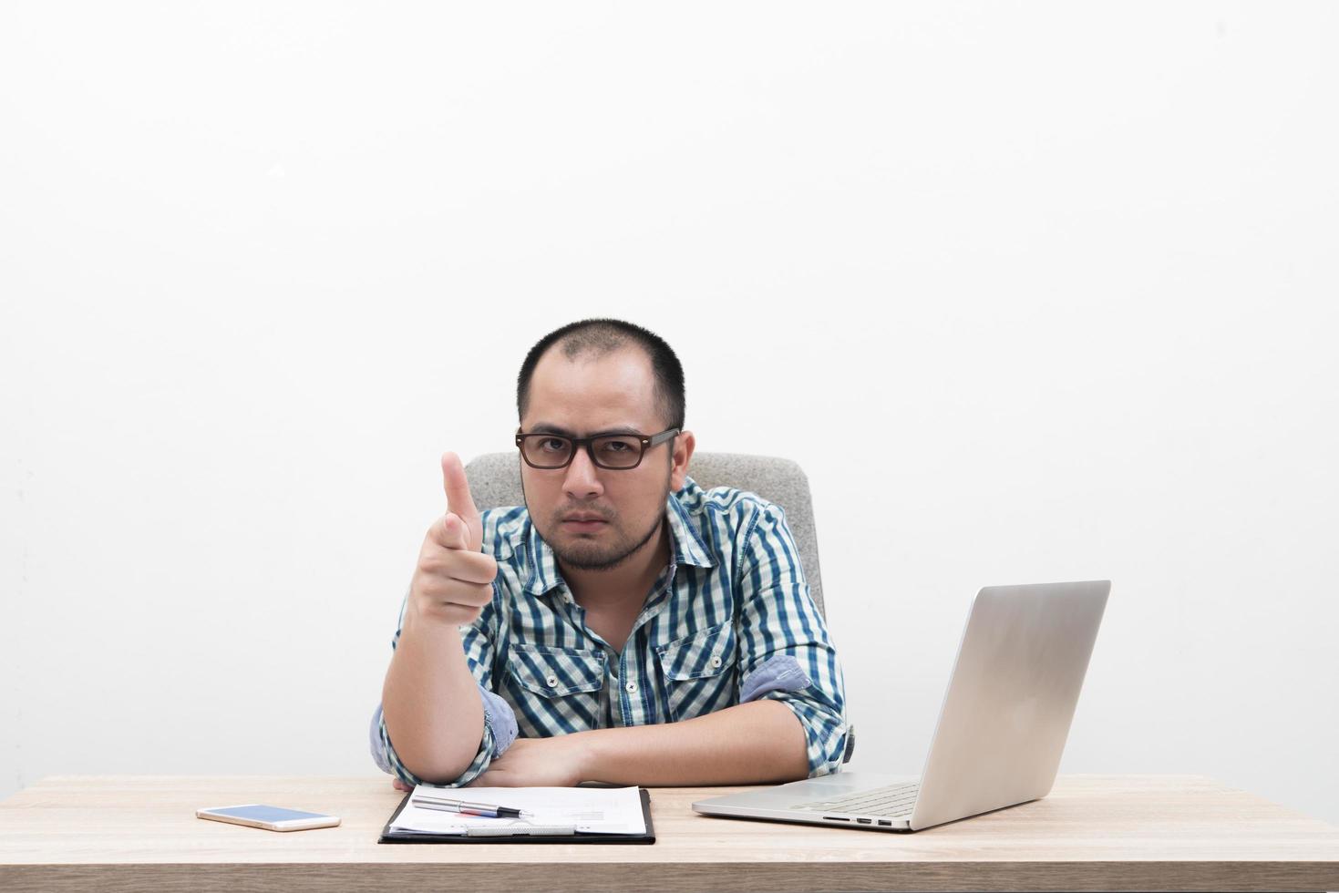 retrato de jovem empresário com polegares para cima sentado no local de trabalho foto