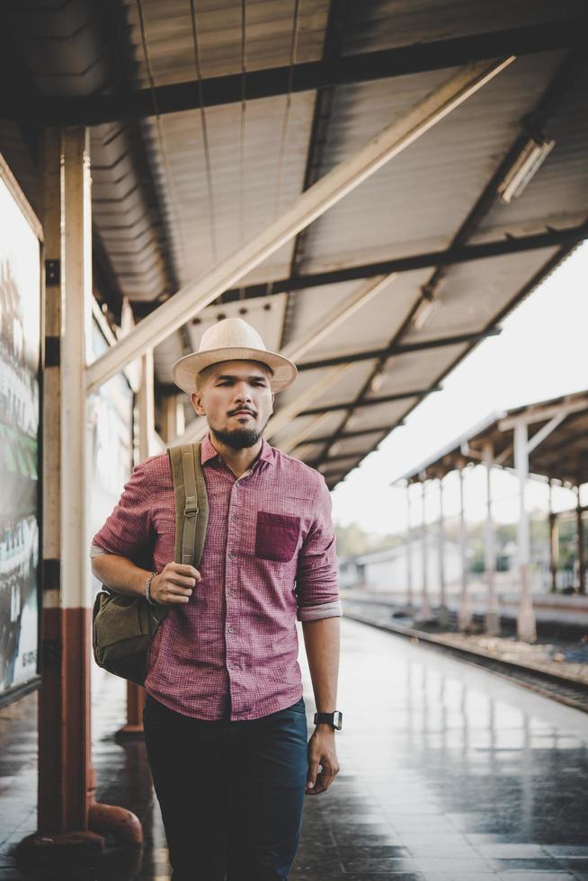 jovem hippie andando pela estação de trem foto