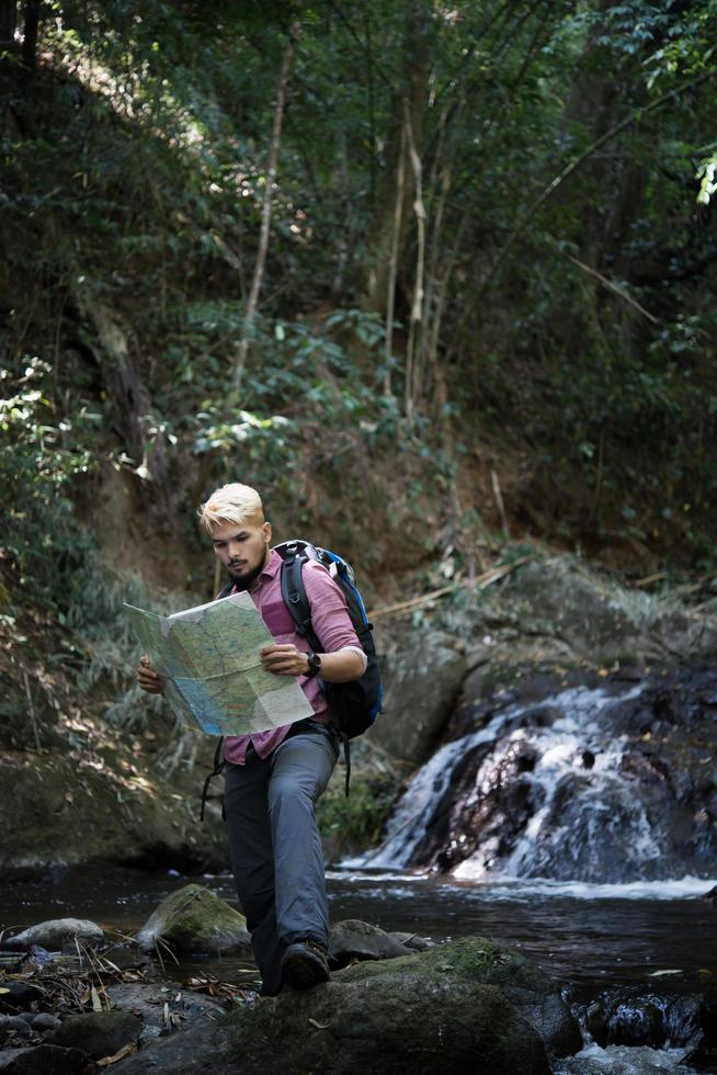 aventureiro observando mapa em um caminho de montanha foto