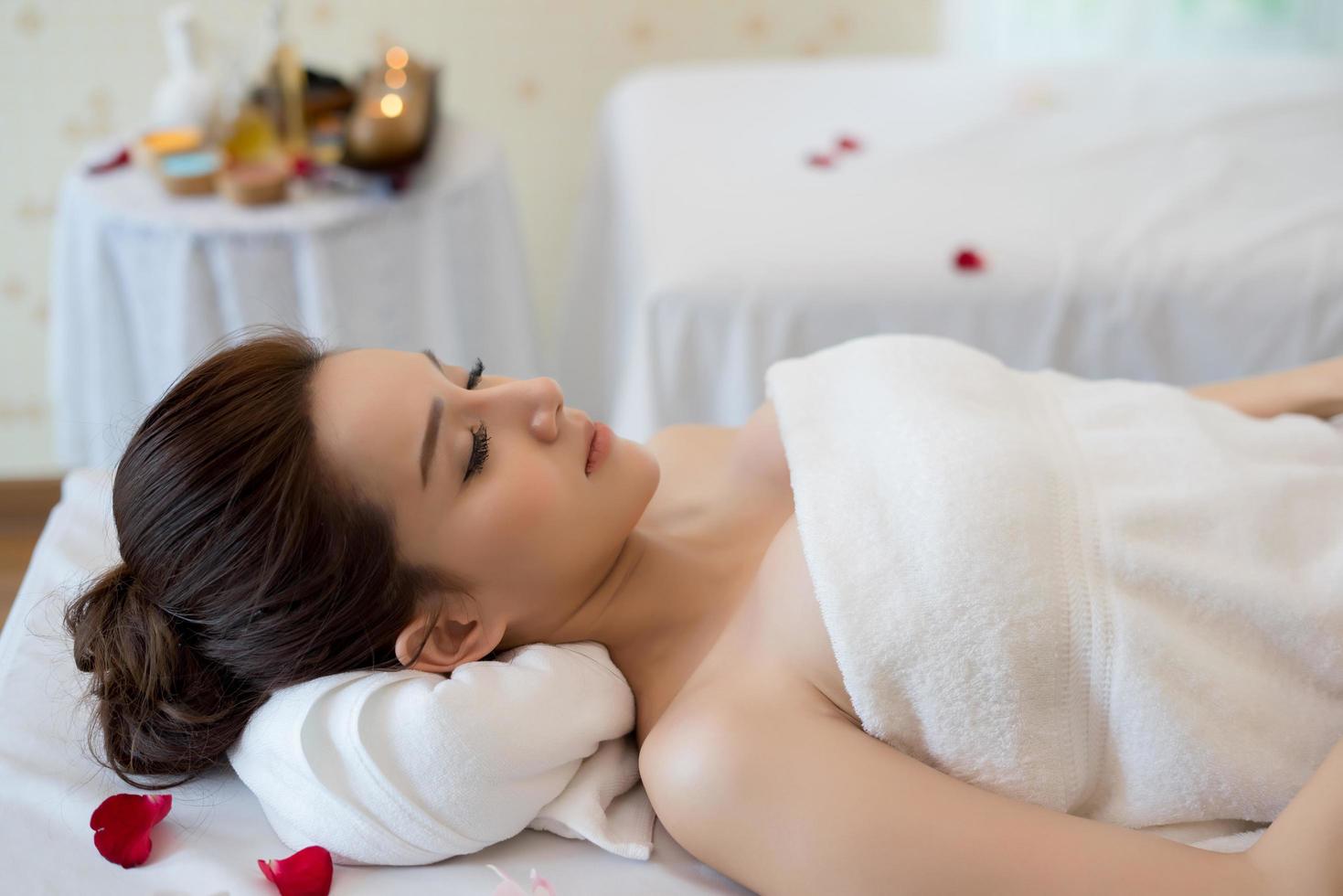 linda mulher sorridente com flores descansando no spa antes da massagem foto