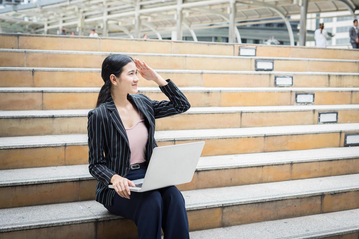 mulher de negócios usando laptop sentada nos degraus foto