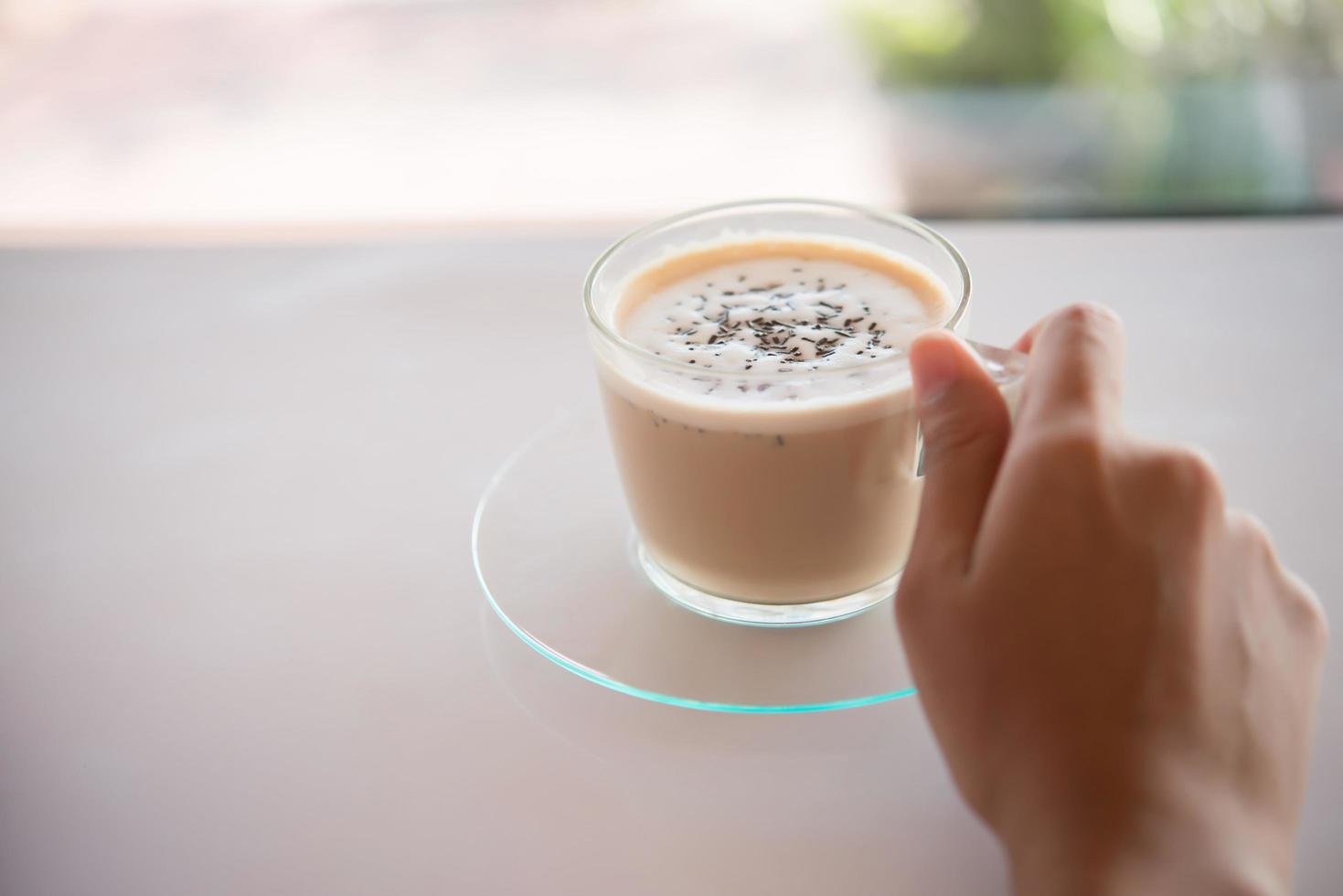 a mão de uma mulher com uma xícara de café em um café foto