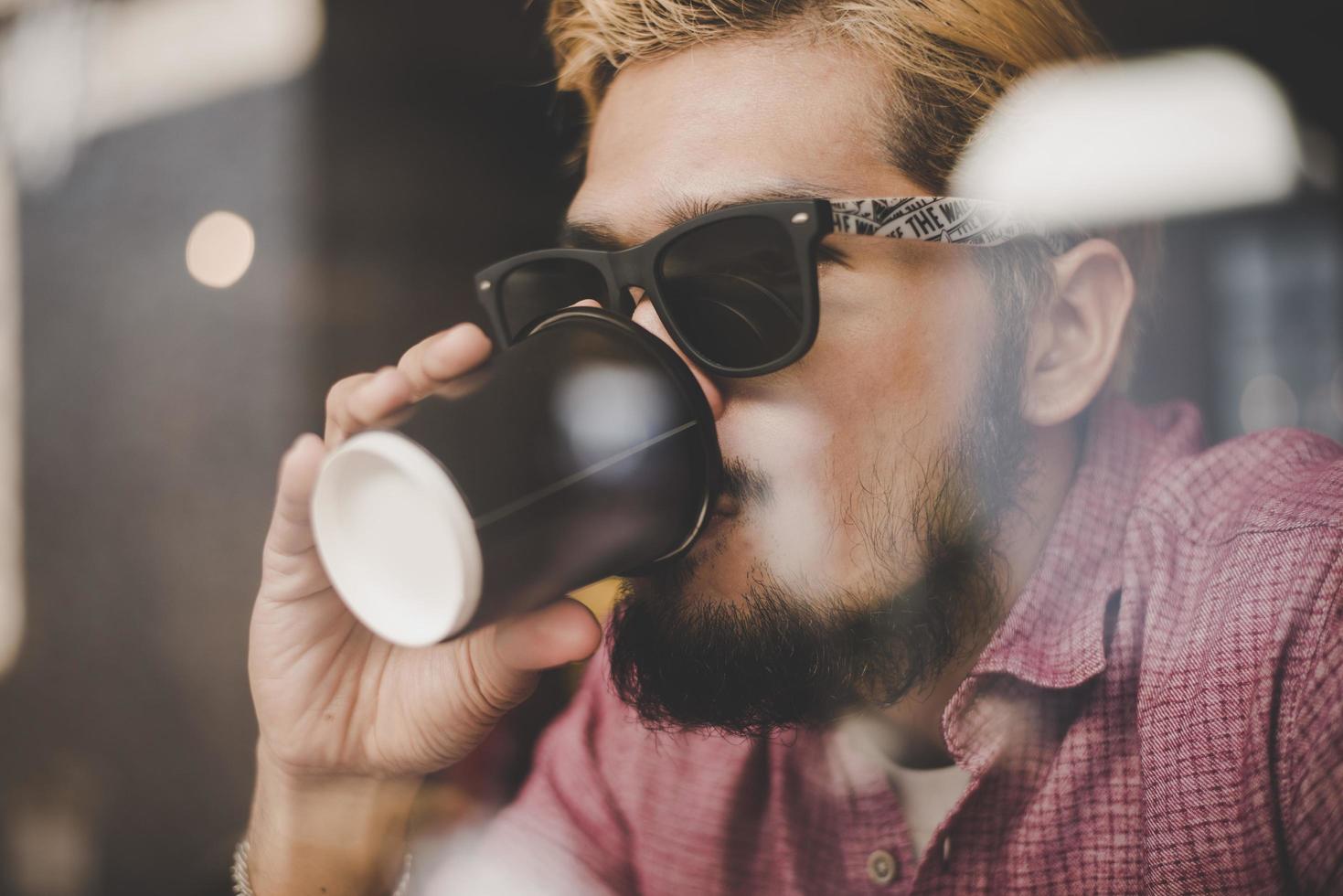 jovem sentado em um café e bebendo um café foto