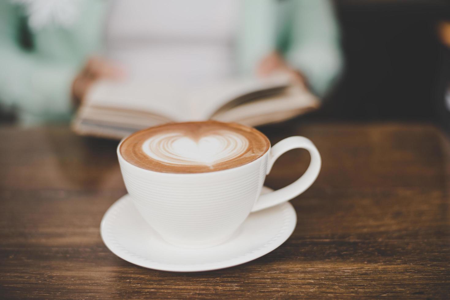 homem borrado lendo e tomando café em um café foto