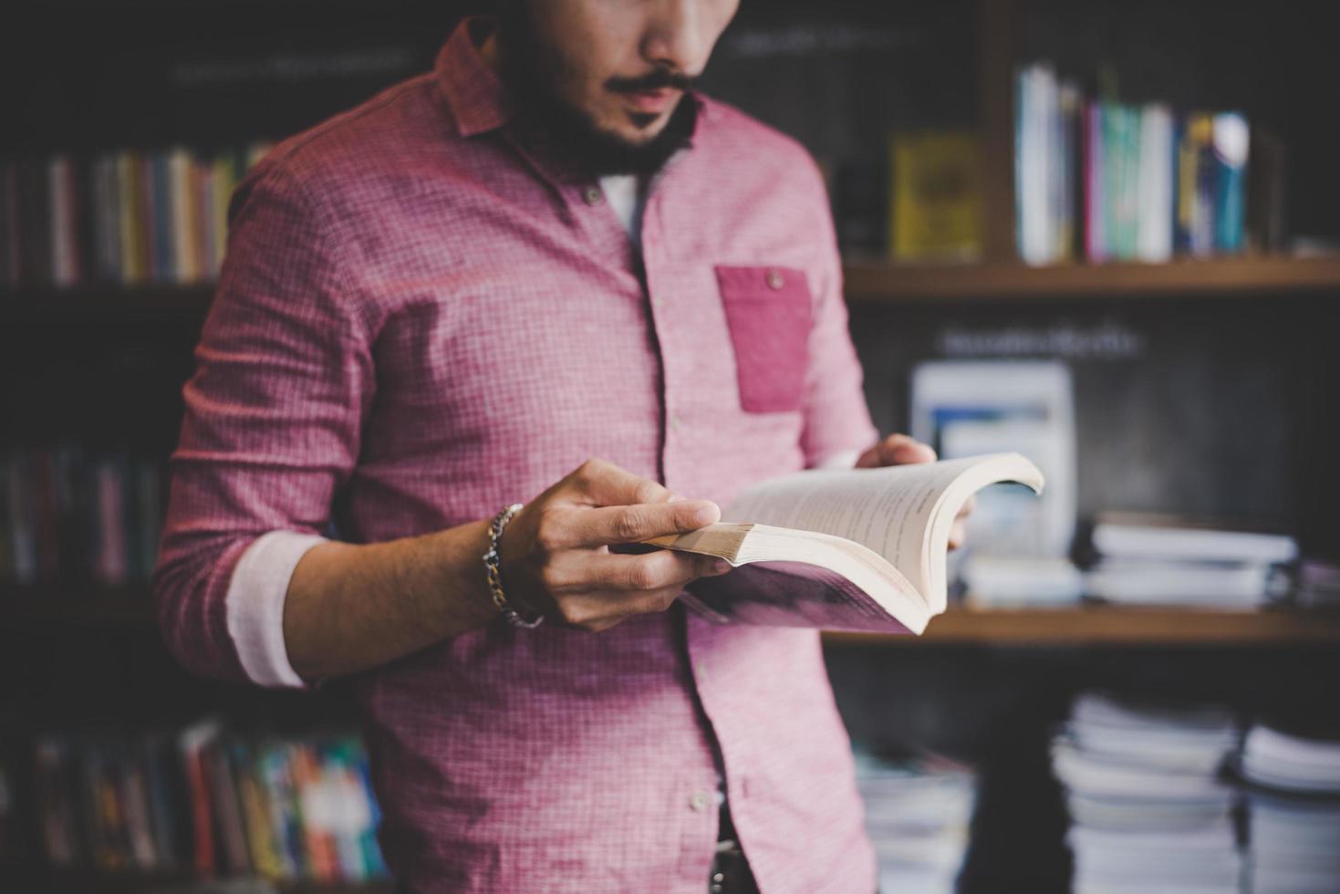 jovem hippie lendo livro em uma biblioteca foto