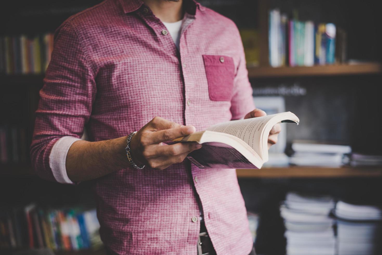 jovem hippie lendo livro em uma biblioteca foto