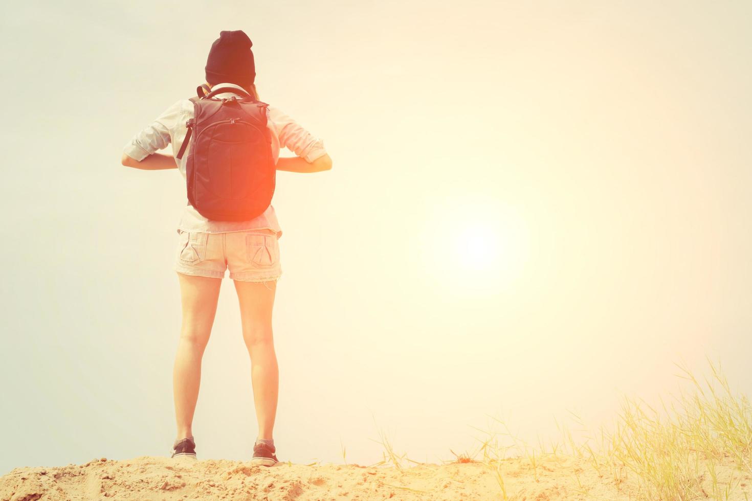 mulher com mochila em pé na praia, conceito de viagens foto