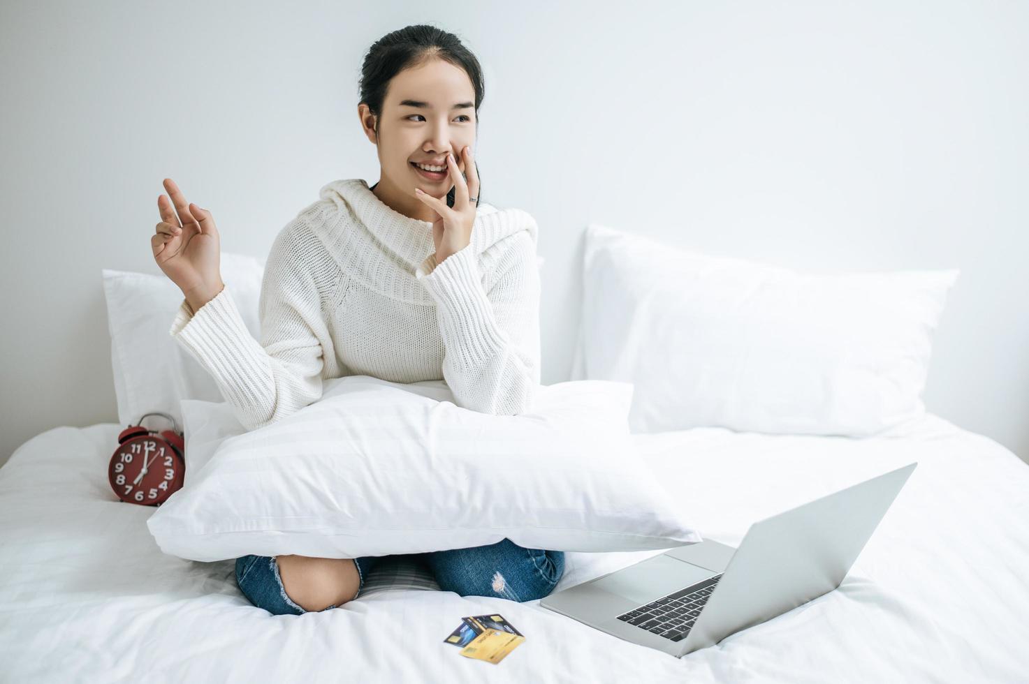 jovem sentada na cama sorrindo alegremente foto