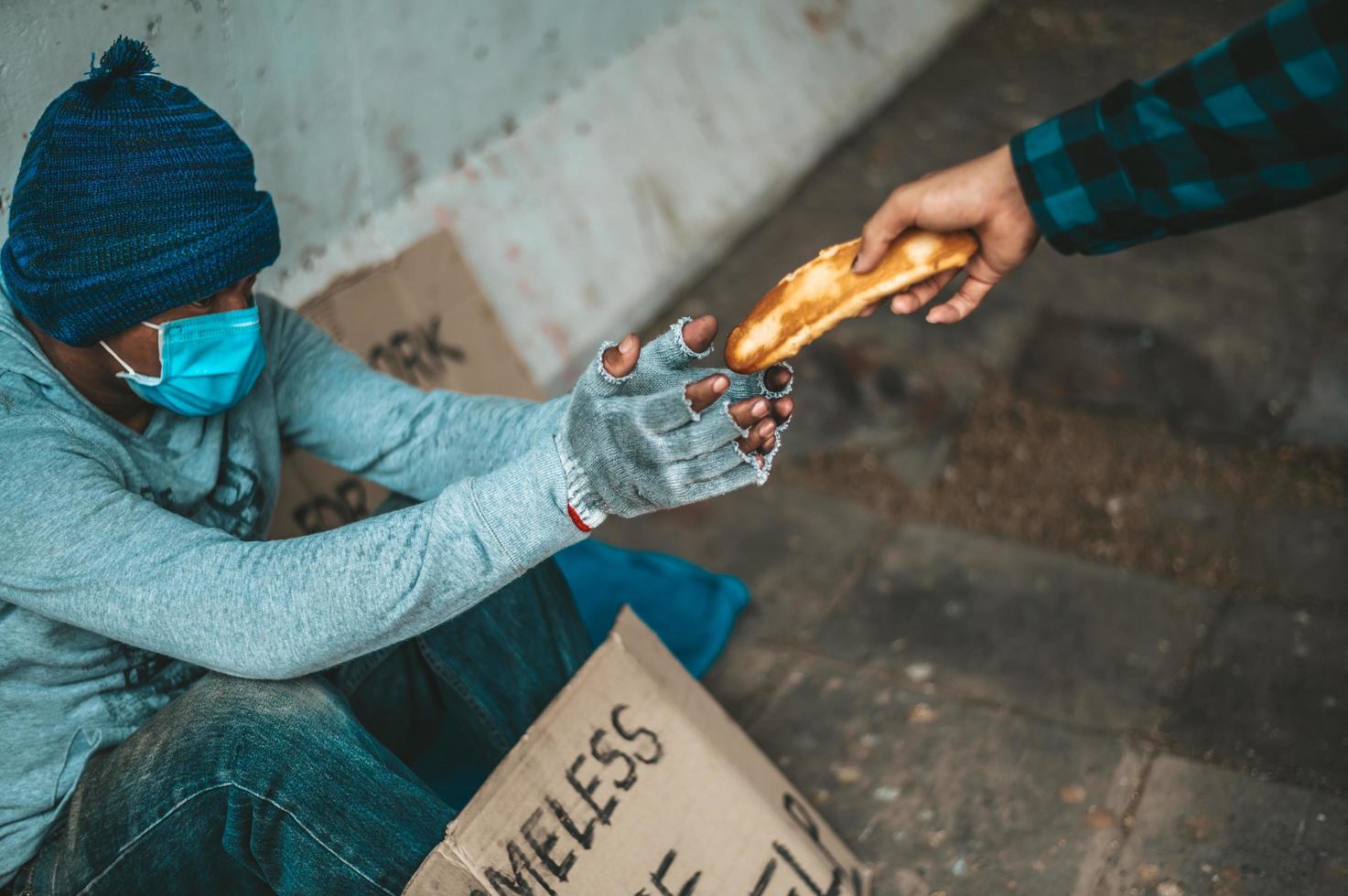 fabricante de pão dá para um mendigo na beira da estrada foto