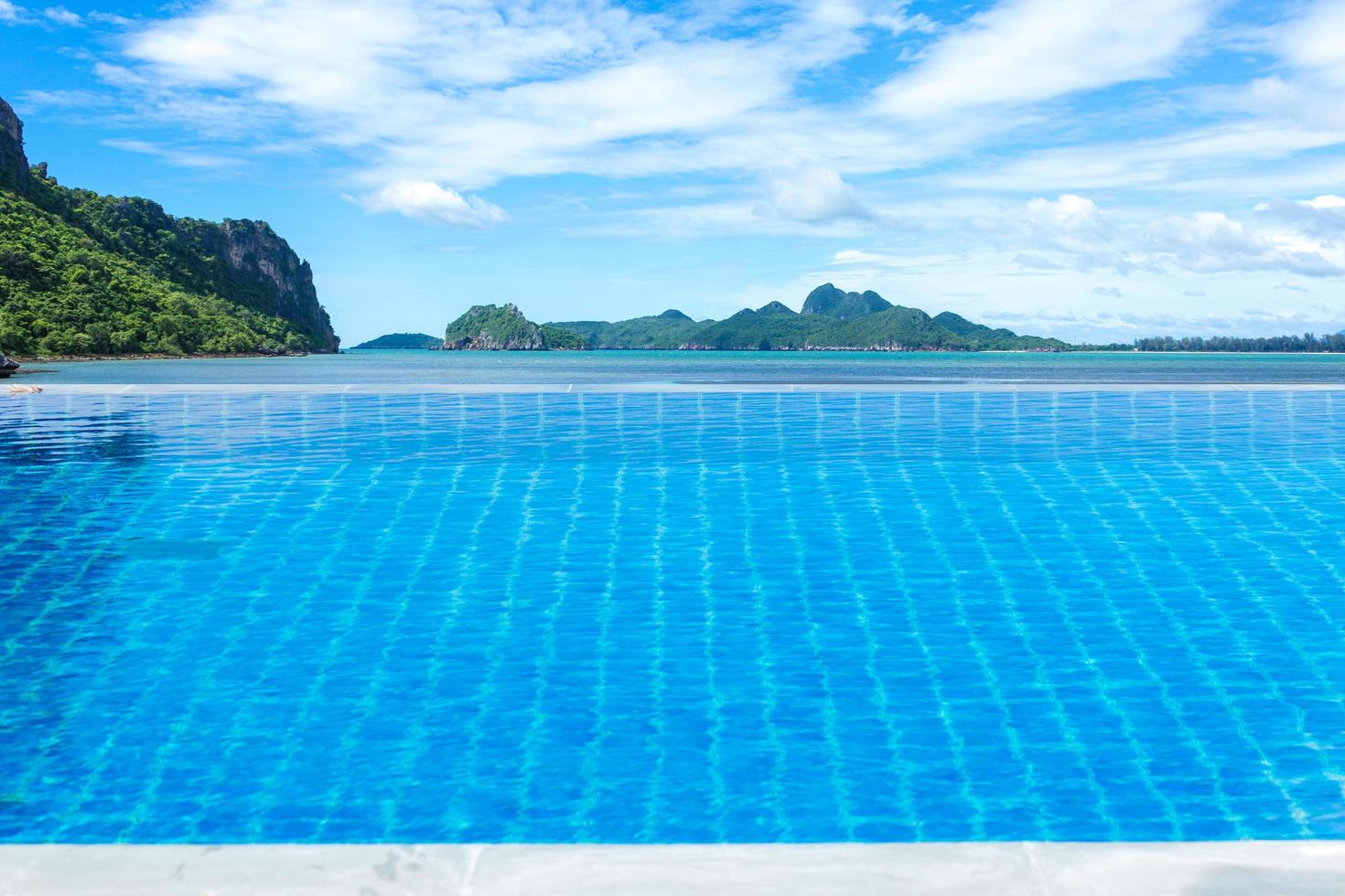 piscina com oceano, montanhas e céu azul nublado foto