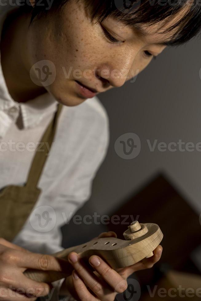 jovem fabricante de violino chinês trabalhando em sua oficina foto