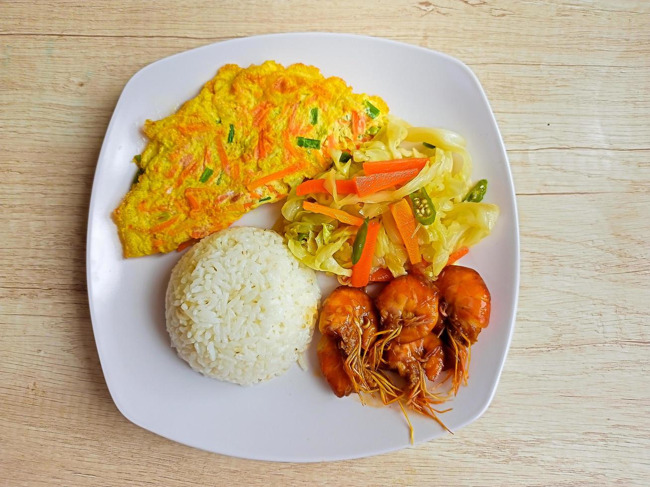 prato de comida saudável de arroz branco com omelete e camarão chili no prato branco sobre a mesa, vista superior foto