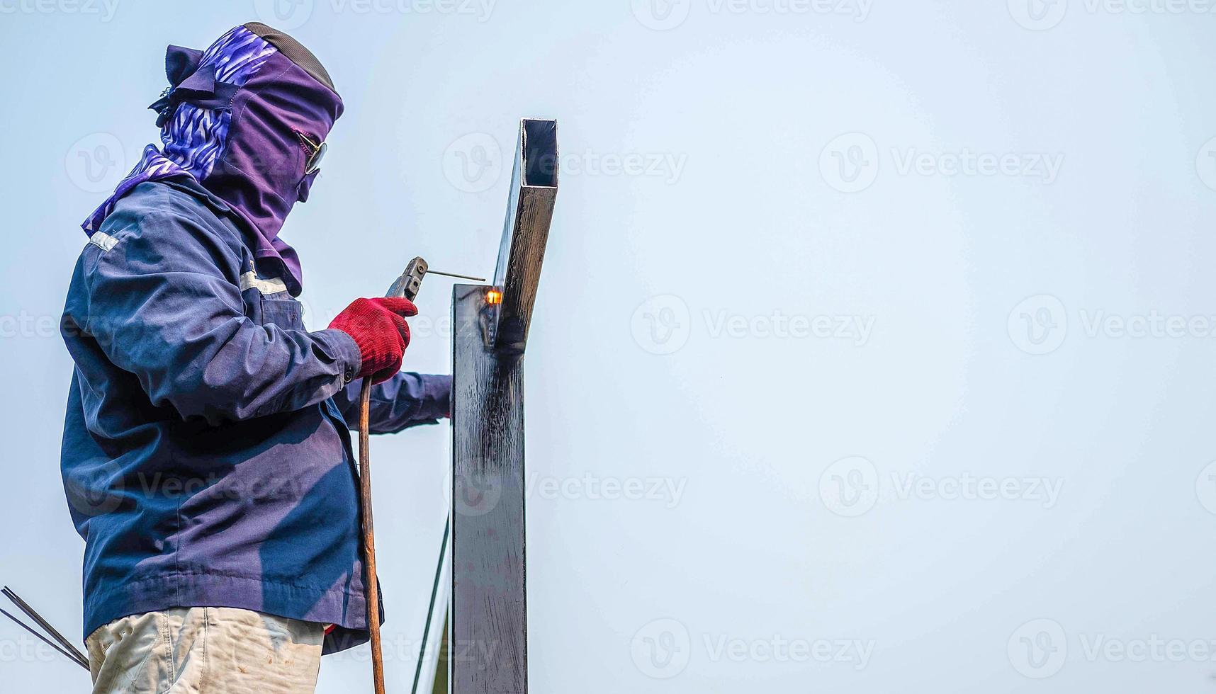 o trabalhador soldador nas roupas de trabalho usa ferramentas de soldagem de aço. soldagem de grandes barras de aço de aço no canteiro de obras foto