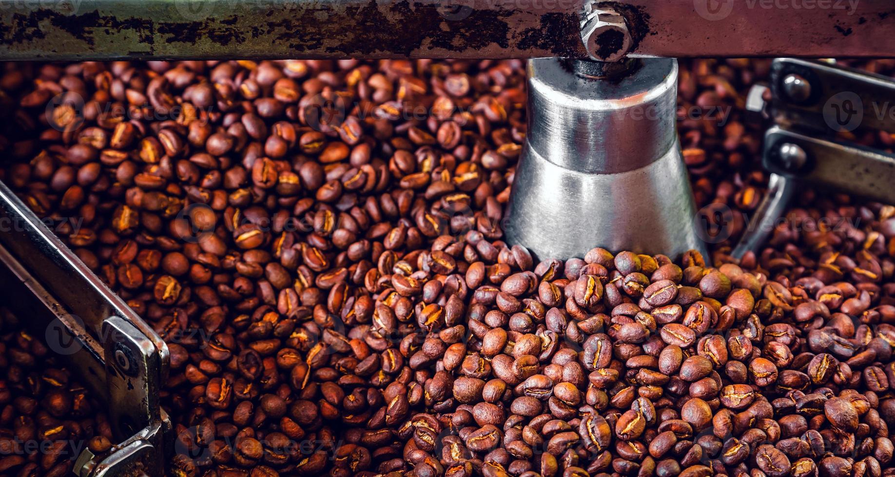 grãos de café aromáticos recém-torrados em uma moderna máquina de torrefação de café. foto